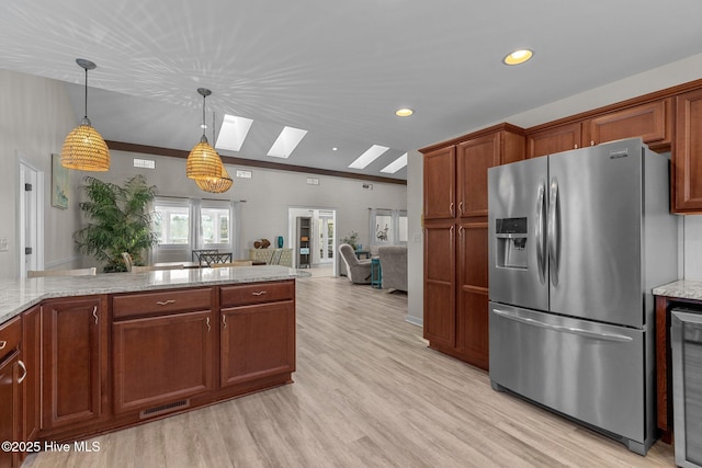 kitchen featuring stainless steel fridge, light hardwood / wood-style flooring, a skylight, light stone counters, and decorative light fixtures