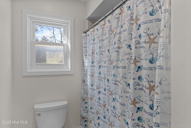 bathroom featuring toilet and curtained shower