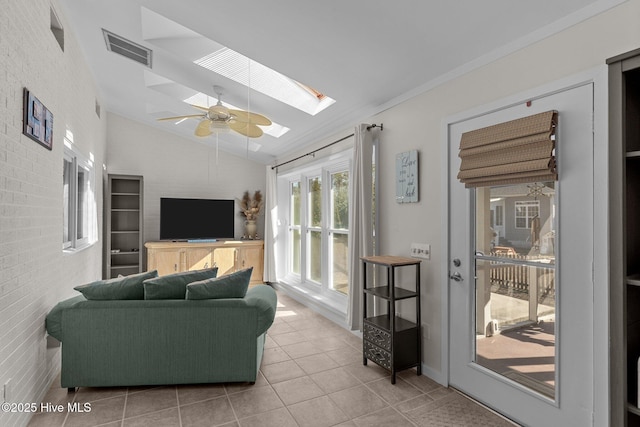 living room featuring vaulted ceiling with skylight, tile patterned floors, and ceiling fan