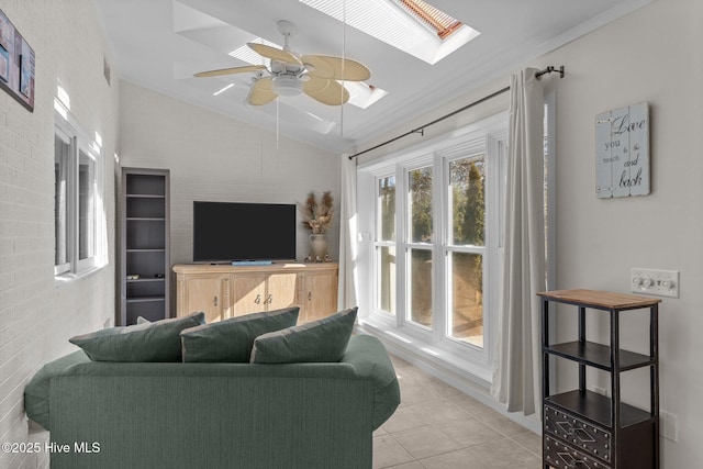 living room with light tile patterned floors, ornamental molding, ceiling fan, brick wall, and vaulted ceiling with skylight