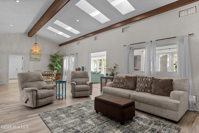 living room featuring a skylight, high vaulted ceiling, light hardwood / wood-style floors, and beamed ceiling