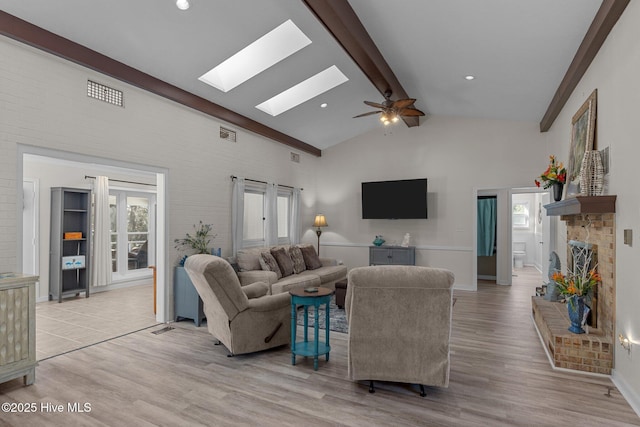 living room with plenty of natural light, beamed ceiling, and light wood-type flooring