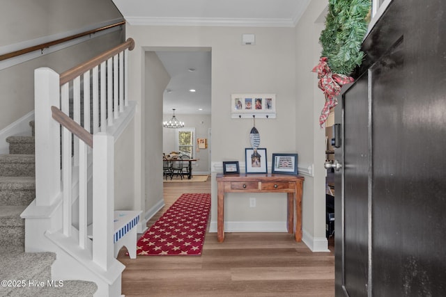 foyer entrance featuring an inviting chandelier, hardwood / wood-style floors, and crown molding