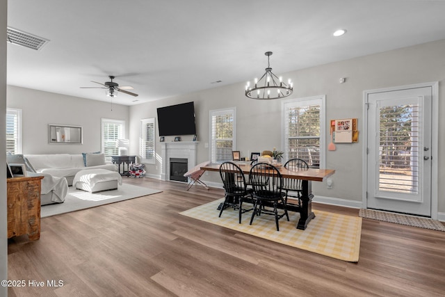 451 Gretchen Rd, West End, NC 27376 - dining room featuring a glass covered fireplace, wood finished floors, visible vents, and ceiling fan with notable chandelier