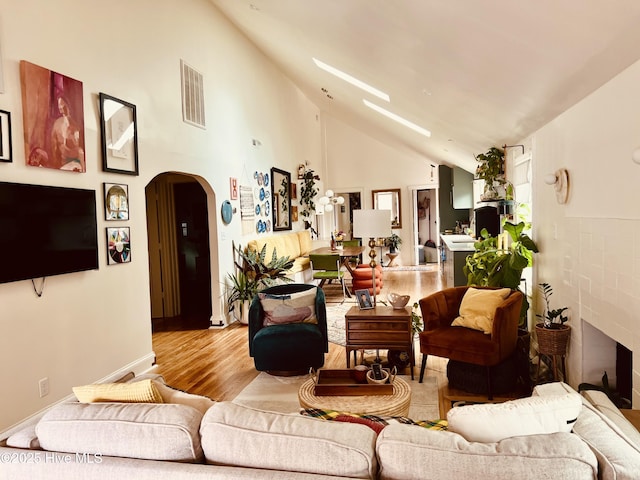 living room with high vaulted ceiling and light hardwood / wood-style flooring