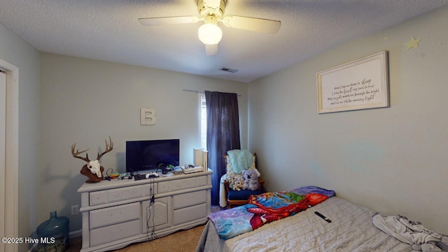 carpeted bedroom featuring ceiling fan and a textured ceiling