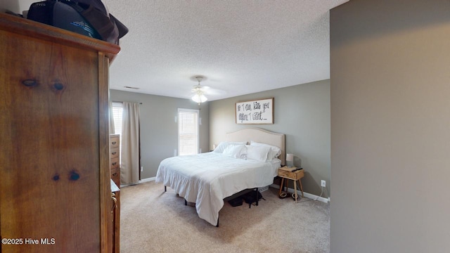 bedroom with ceiling fan, light carpet, and a textured ceiling