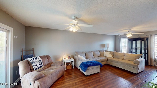 living room featuring dark wood-type flooring, ceiling fan, and a textured ceiling