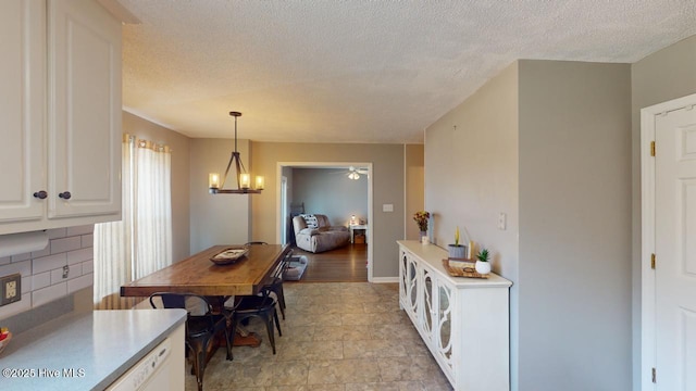 dining space with ceiling fan with notable chandelier and a textured ceiling