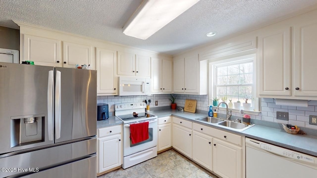 kitchen featuring backsplash, white appliances, sink, and white cabinets