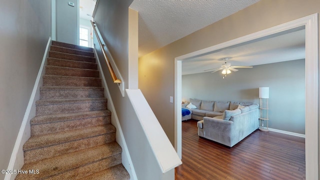 stairway featuring hardwood / wood-style flooring, ceiling fan, and a textured ceiling