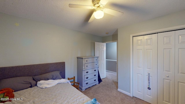 carpeted bedroom with ceiling fan, a closet, and a textured ceiling