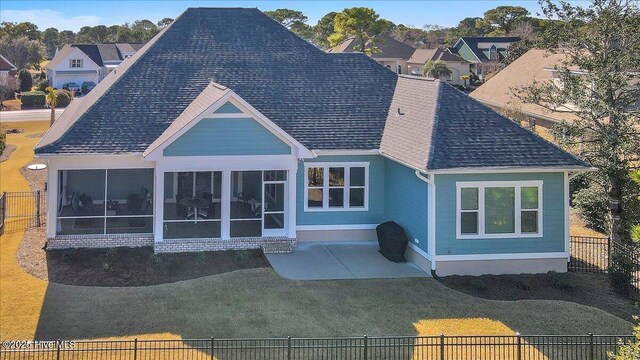 rear view of property featuring a patio area, a sunroom, and a lawn