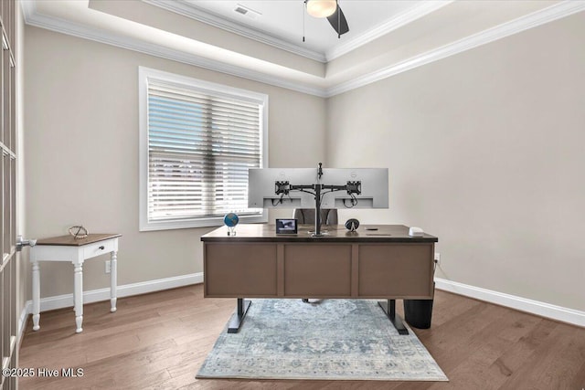 office space with a tray ceiling, ornamental molding, ceiling fan, and light wood-type flooring