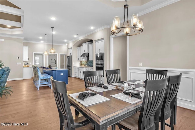 dining room featuring sink, light hardwood / wood-style flooring, and ornamental molding