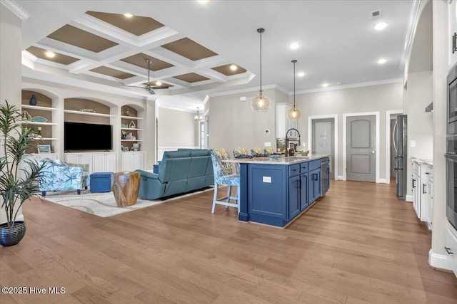 kitchen with blue cabinets, an island with sink, a breakfast bar area, white cabinets, and hanging light fixtures