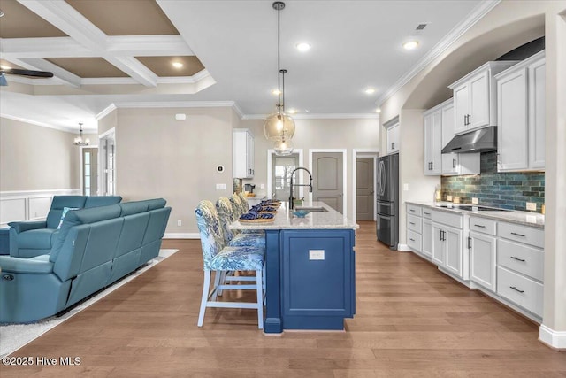 kitchen with sink, decorative light fixtures, an island with sink, and white cabinets