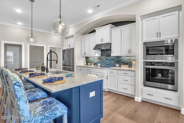 kitchen featuring sink, white cabinetry, decorative light fixtures, a center island with sink, and stainless steel appliances