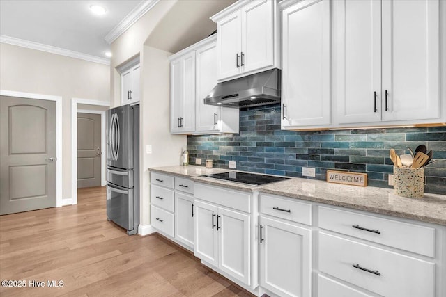 kitchen with white cabinetry, stainless steel fridge, ornamental molding, black electric stovetop, and light hardwood / wood-style flooring