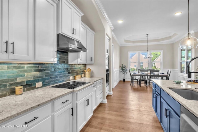 kitchen with sink, blue cabinetry, white cabinetry, black electric stovetop, and decorative light fixtures