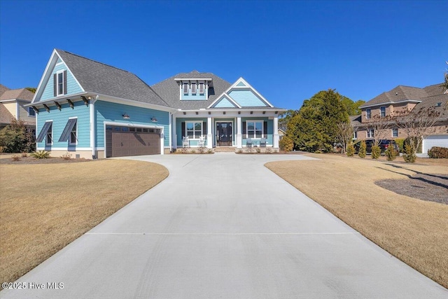 view of front of house featuring a garage, a front lawn, and covered porch