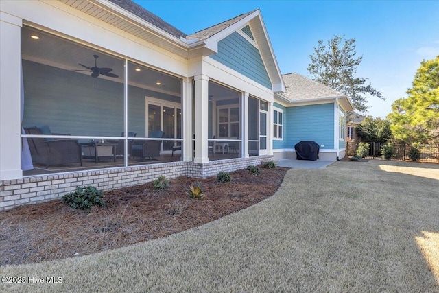 view of home's exterior with a lawn, a sunroom, and ceiling fan