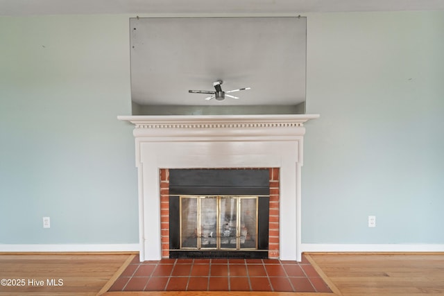 room details featuring hardwood / wood-style flooring, ceiling fan, and a brick fireplace