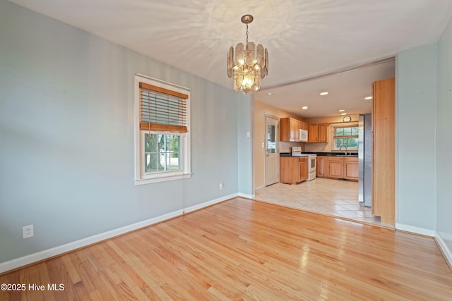 unfurnished living room with a notable chandelier and light hardwood / wood-style floors