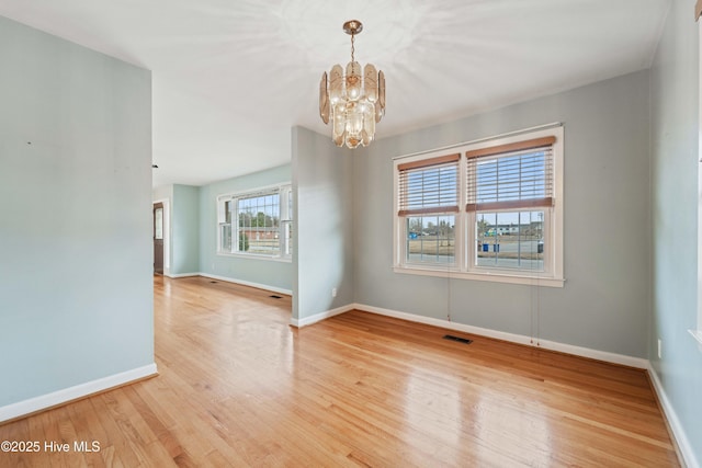 unfurnished room with a chandelier and light hardwood / wood-style floors