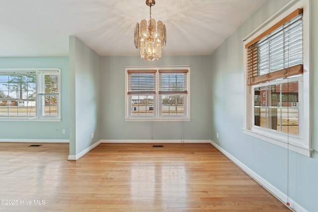 unfurnished dining area featuring a notable chandelier and light wood-type flooring