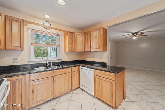 kitchen featuring sink, light tile patterned floors, dishwasher, range, and dark stone countertops