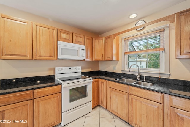 kitchen with light tile patterned flooring, sink, dark stone countertops, and white appliances