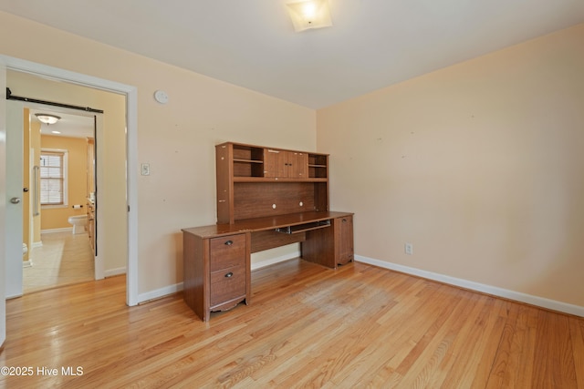 office featuring a barn door and light hardwood / wood-style floors