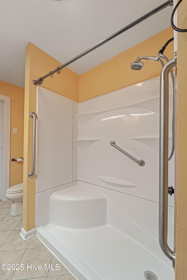 bathroom featuring toilet, tile patterned flooring, and a shower