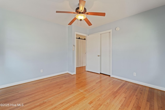 spare room with light hardwood / wood-style floors, a barn door, and ceiling fan