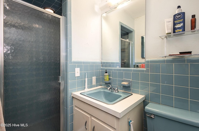 bathroom with vanity, toilet, a shower with door, and tile walls