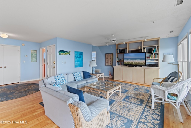 living room featuring light hardwood / wood-style floors, rail lighting, and ceiling fan