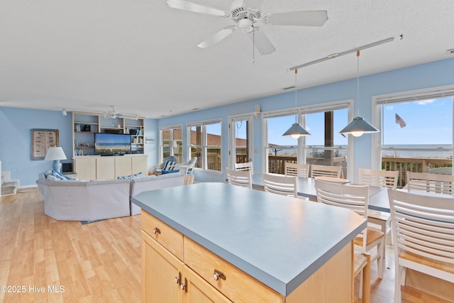 kitchen featuring light hardwood / wood-style flooring, ceiling fan, hanging light fixtures, a textured ceiling, and light brown cabinets