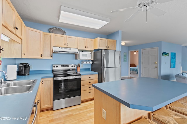 kitchen with sink, light hardwood / wood-style flooring, ceiling fan, appliances with stainless steel finishes, and light brown cabinets