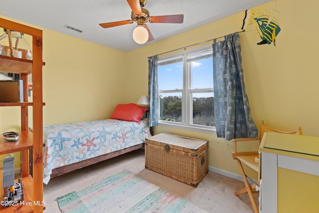 bedroom with ceiling fan, light carpet, and a textured ceiling