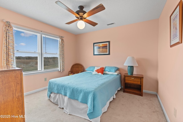 carpeted bedroom with ceiling fan and a textured ceiling