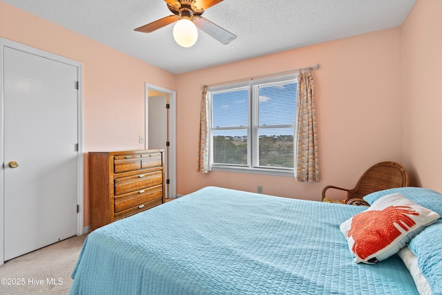 carpeted bedroom featuring ceiling fan and a textured ceiling