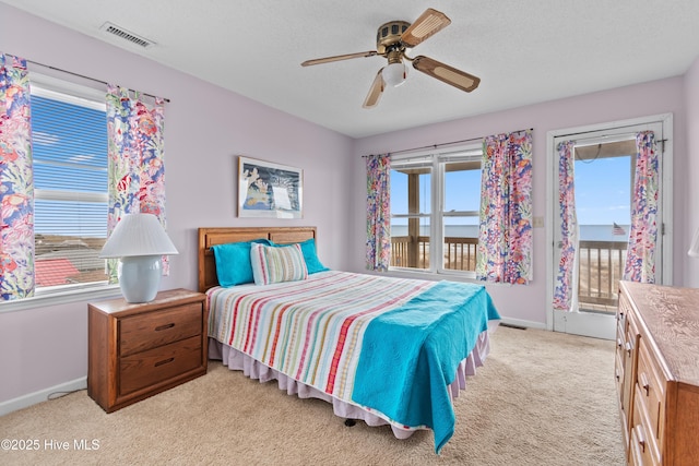 carpeted bedroom featuring ceiling fan, access to outside, a textured ceiling, and a water view