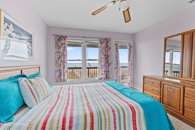 bedroom with a water view, ceiling fan, and access to exterior