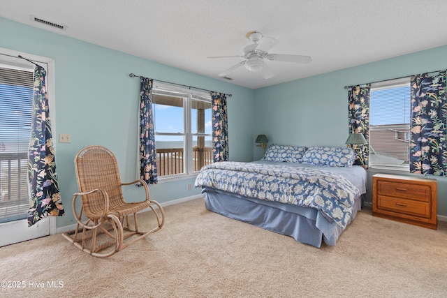 bedroom with multiple windows, ceiling fan, light colored carpet, and a textured ceiling