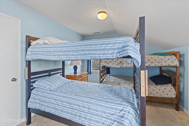 bedroom with light colored carpet, vaulted ceiling, and a textured ceiling