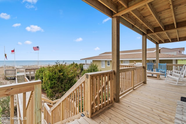 wooden deck with a water view and a beach view