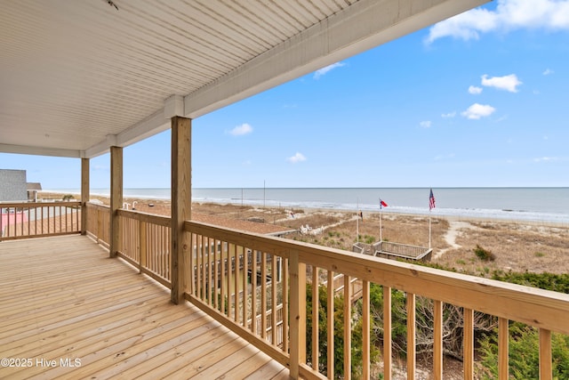 wooden deck with a water view and a beach view