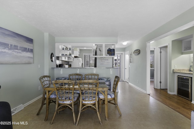 dining space with wine cooler, indoor bar, and a textured ceiling