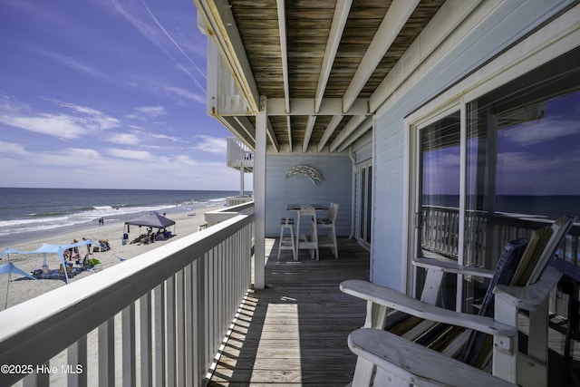 balcony with a water view and a view of the beach